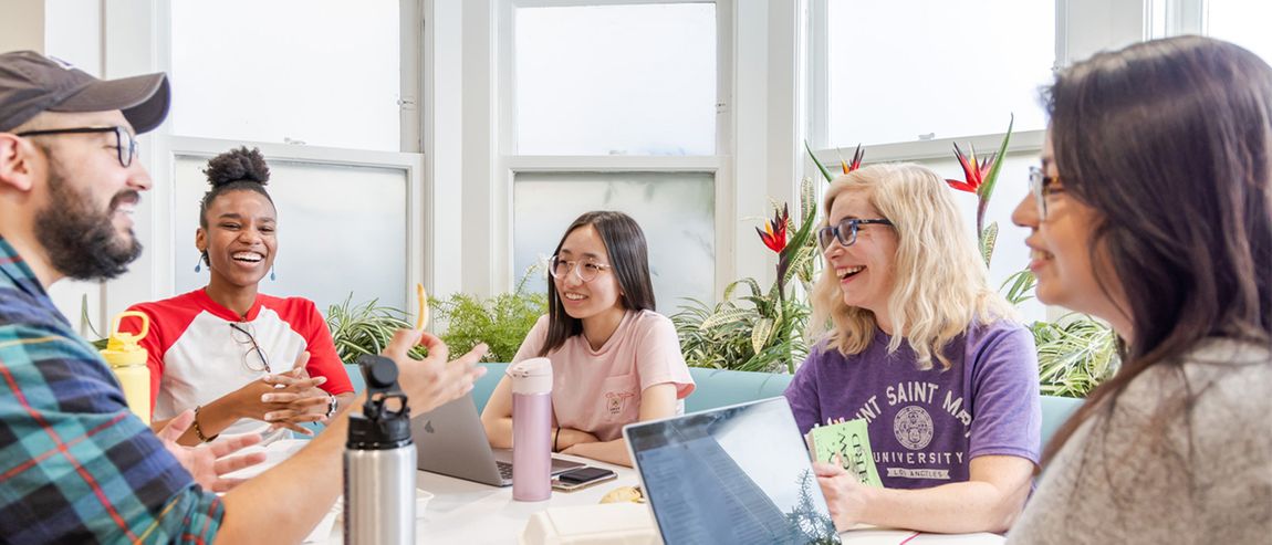 group of students talking and working at a table.