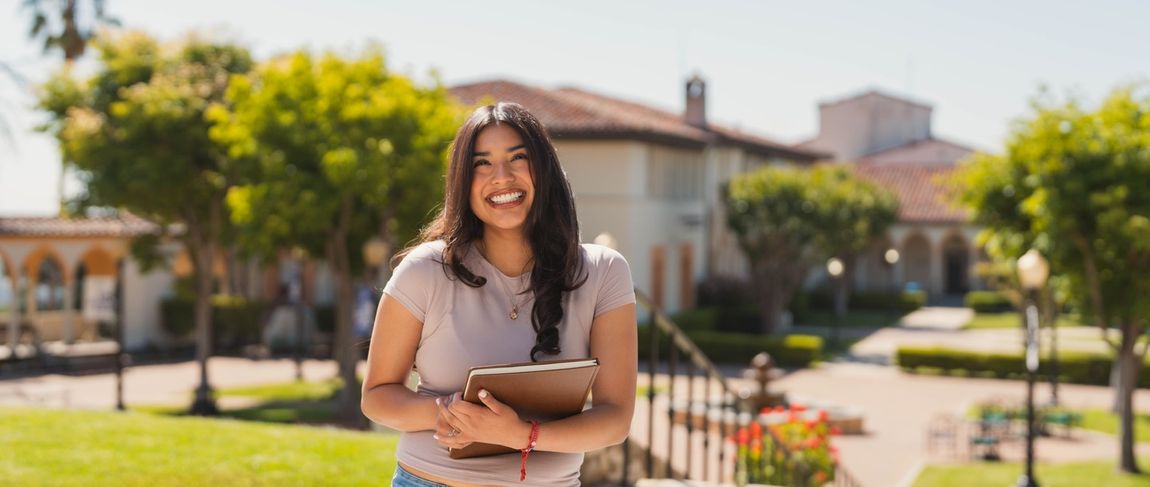 female student smiling holding a notebook on the chalon campus