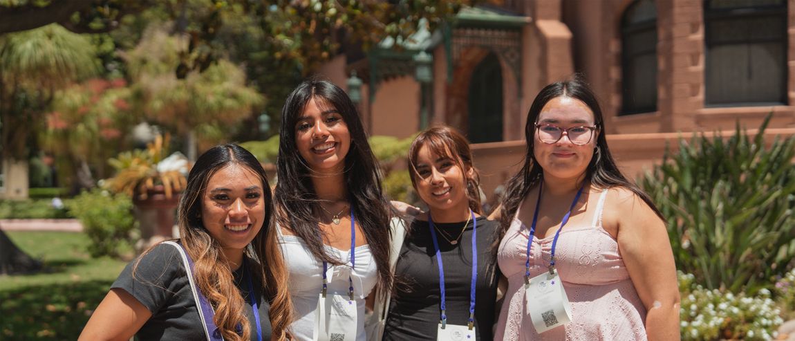 group of female students smiling wearing lanyards standing outdoors