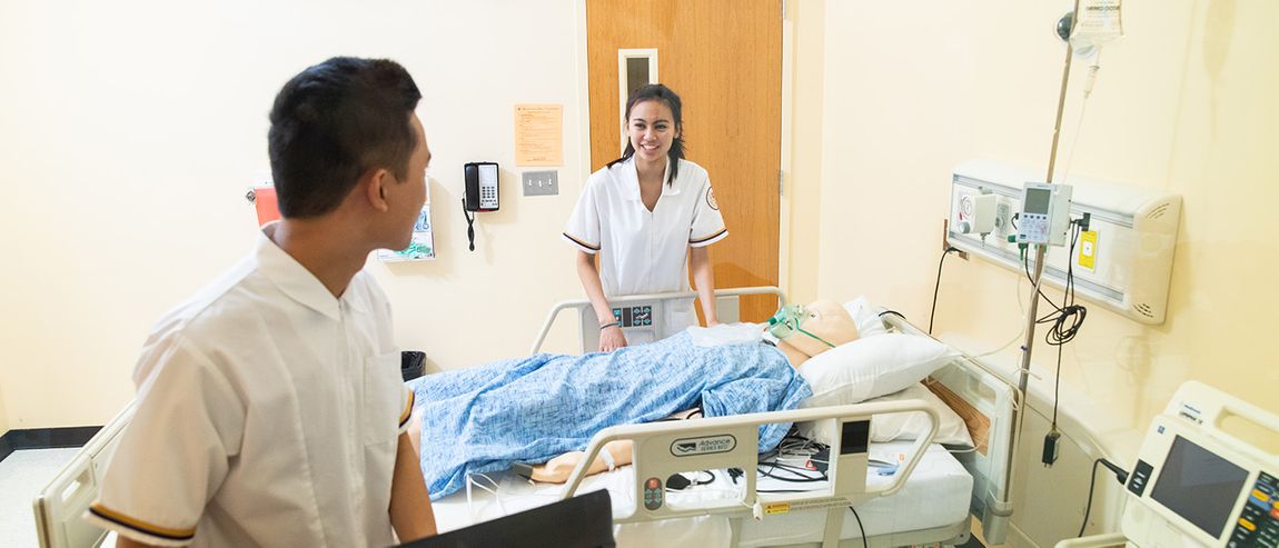 nursing students in white coats tending to a dummy patient
