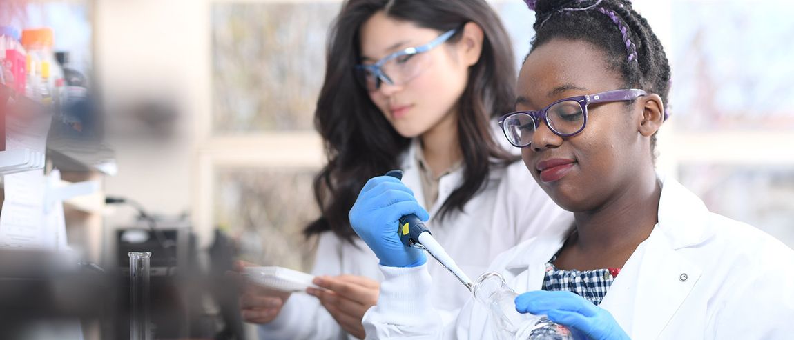 Two students in labcoats doing science things