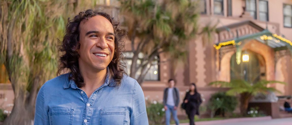 male student smiling with students in background walking on Doheny campus