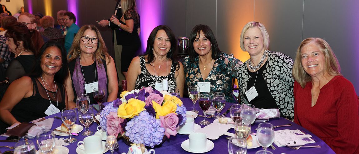 a group of alumnae smiling and sitting together at an alumnae event