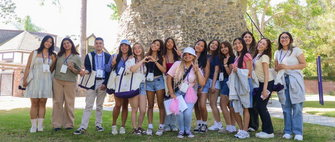 group of orientation leaders (students) standing on campus smiling