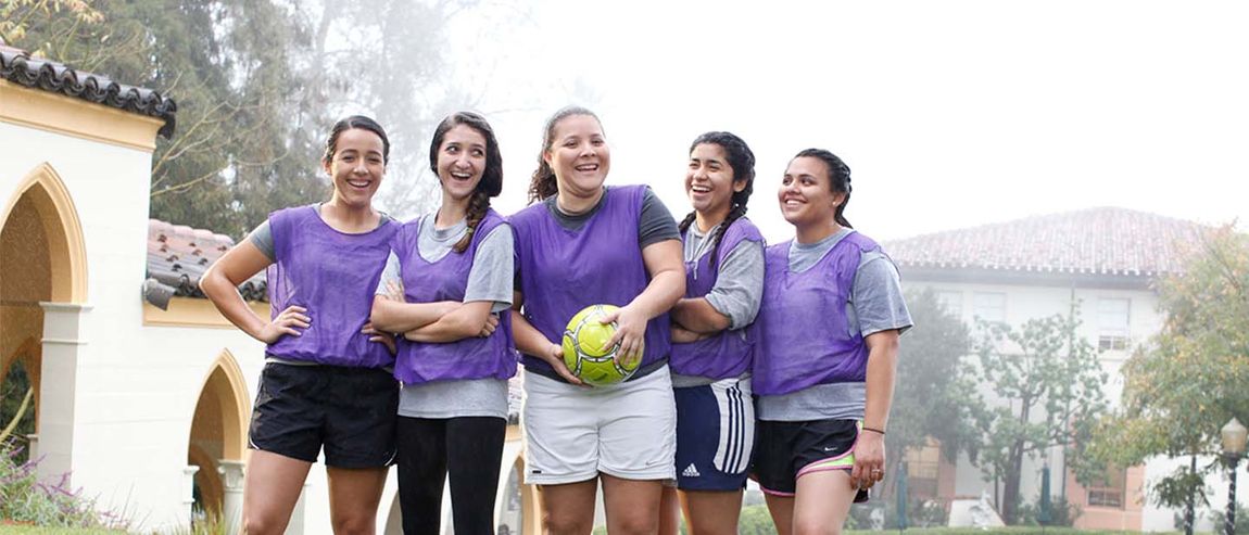 group of girls smiling holding a soccer ball