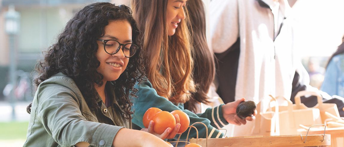 Students holding fruits at a farmers market