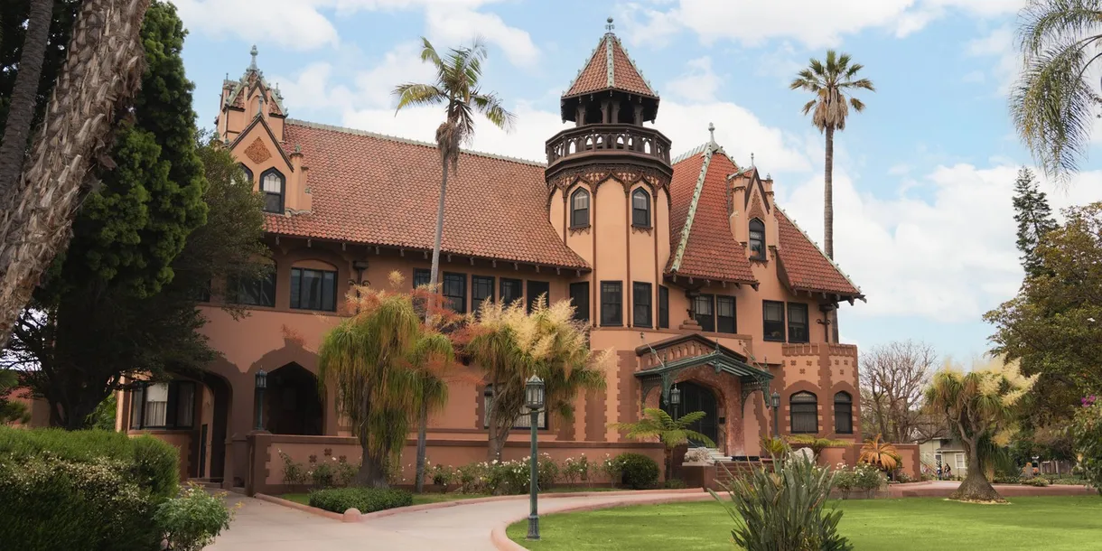 doheny mansion, brown and red historical mansion with a green lawn in front and palm trees