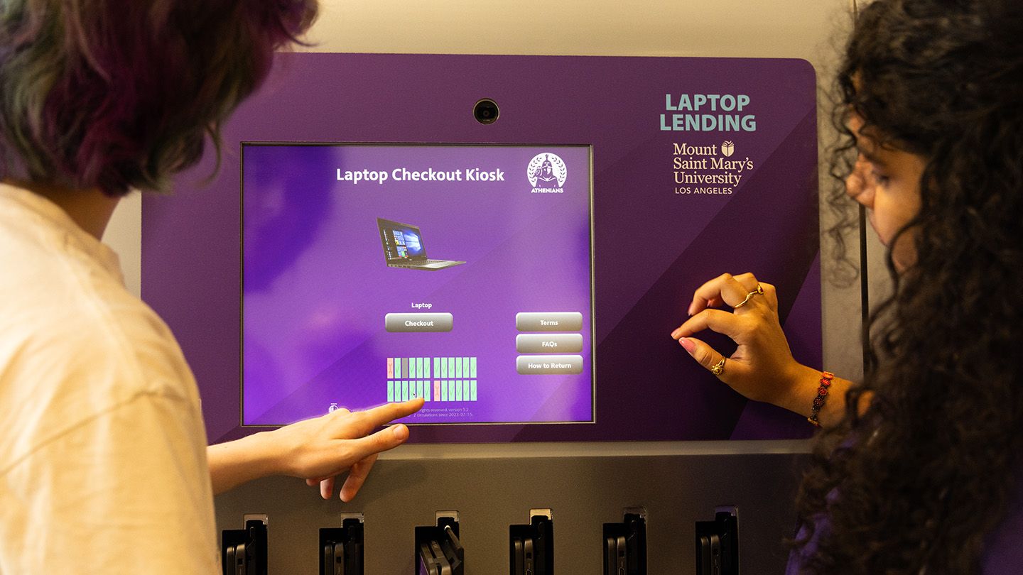Students interacting with a laptop kiosk