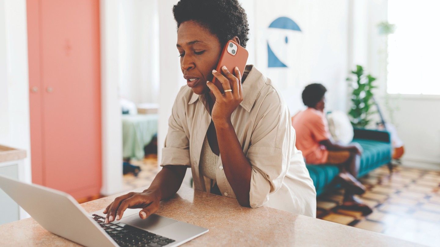 Woman looking at her laptop while talking on the phone.