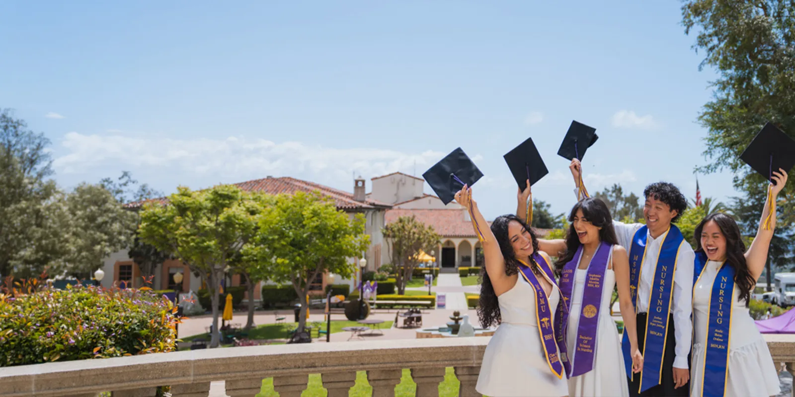Four �鶹��ýӳ�� grads celebrating holding their caps on Chalon Campus