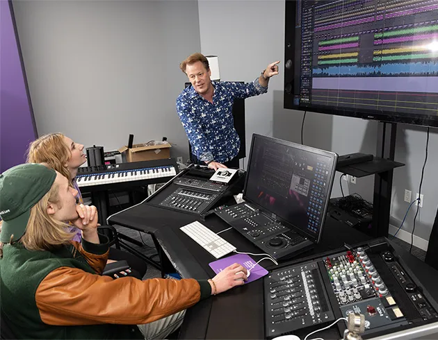 Instructor Kelby Thwaits and students editing a project in the 5.1 surround sound editing bay.