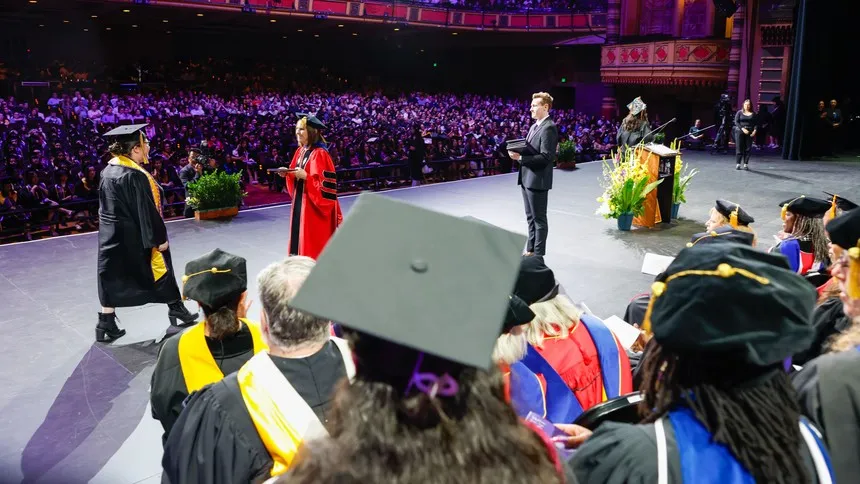 A graduate crosses the stage to receive her diploma from President McElaney-Johnson.
