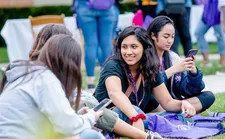 Two students sitting in the grass and talking