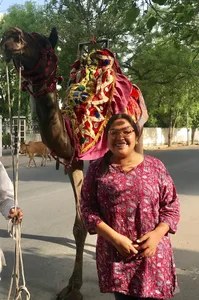 Portrait of a woman in front of a camel.