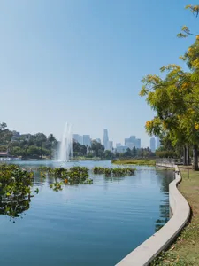 pond with trees around and downtown los angeles buildings in the background