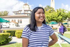 female student in striped shirt and black hair smiling