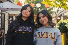 two female students smiling standing outdoors in Little Tokyo wearing ˮ���� sweaters