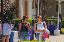 two female students walking and talking on campus with booths behind them