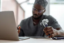 male nurse student working with laptop and notepad at a desk holding a stethoscope
