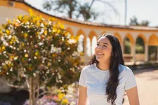 student smiling to the left standing outside on campus