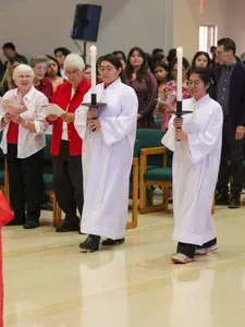 students walking in a catholic mass holding candles