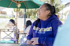 female student laughing sitting outdoors on campus