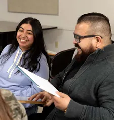 two students sitting in a classroom smiling and discussing