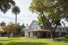 building 10 on doheny campus, a green and white building with palm trees on the left and a larger tree on the right and some green grass in front