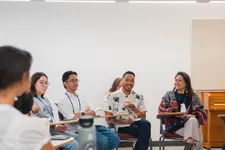 adult students in a classroom setting sitting down, with one man in a white shirt and glasses talking