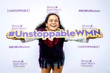 female student with glasses smiling holding an 