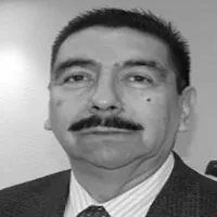 Man with mustache wearing a suit and tie smiling