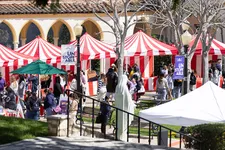 A wide shot of a row of red and white tents with students milling around.
