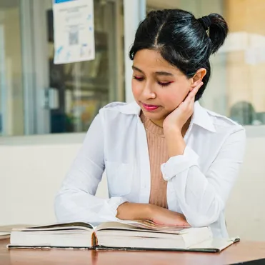 female student in white coat sitting reading a book