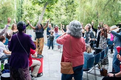 group of people at conference standing in a circle outdoors participating in a drum circle