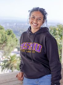 female student in black �鶹��ýӳ�� hoodie smiling standing outdoors with the greater LA area behind her