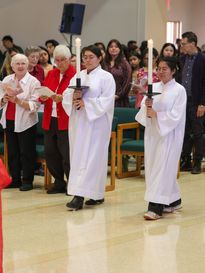 students walking in a catholic mass holding candles