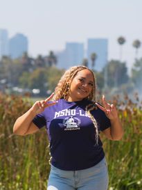 A student posing in front of the LA skyline