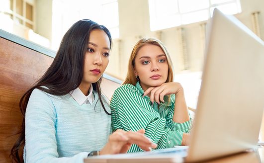 Two students working together on a laptop