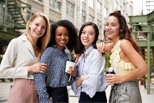 four women walking down the street smiling