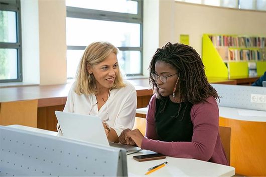 faculty helping graduate student in a classroom setting