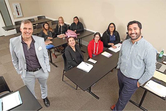 students sitting in room smiling with two male faculty leads
