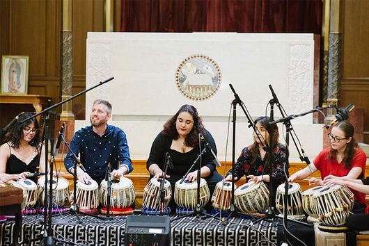 group of people sitting on the ground playing instruments