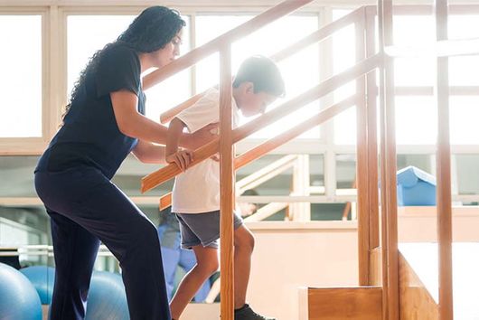 therapist helping a child walk