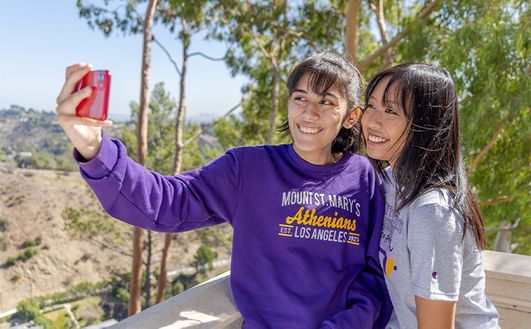 Two students taking a selfie outside