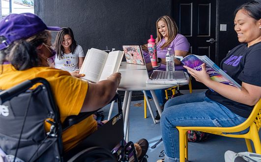 A group of four students reading around a table outside