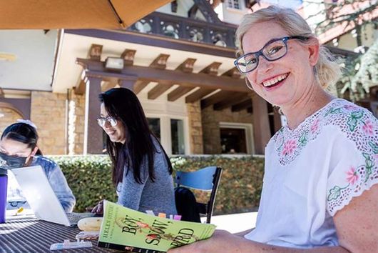 students sitting at outdoor table reading