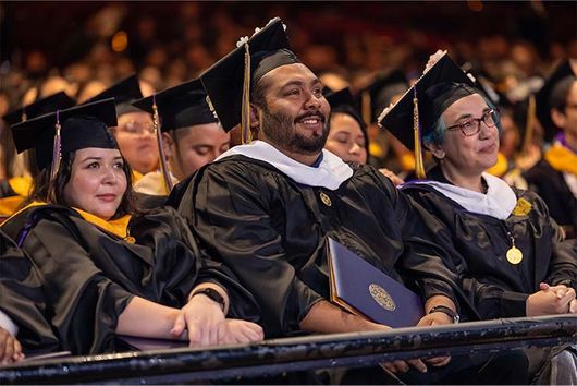 graduting students smiling holding their degrees