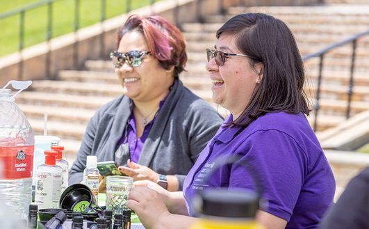 Two people sitting at an event booth outside