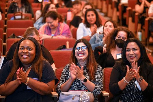 women at event smiling and clapping