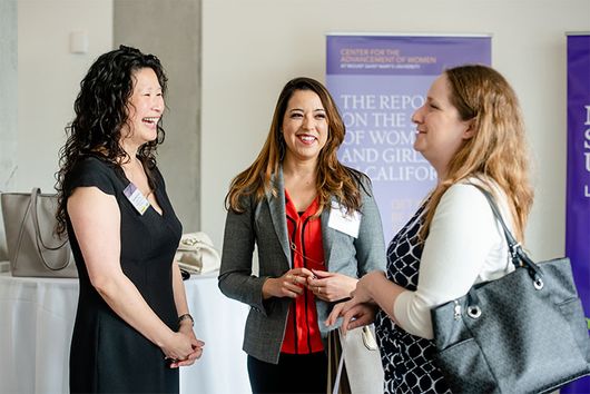 3 women smiling and talking at event